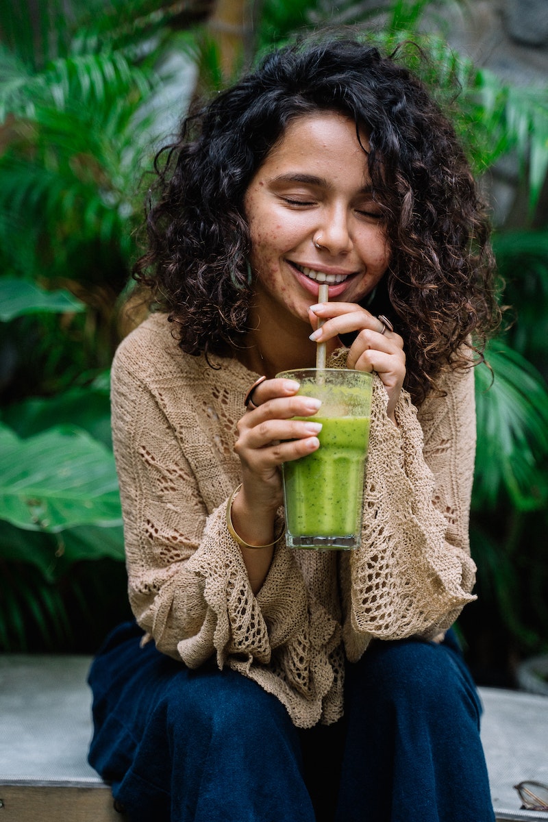 Woman with Curly Hair Drinking Green Smoothie